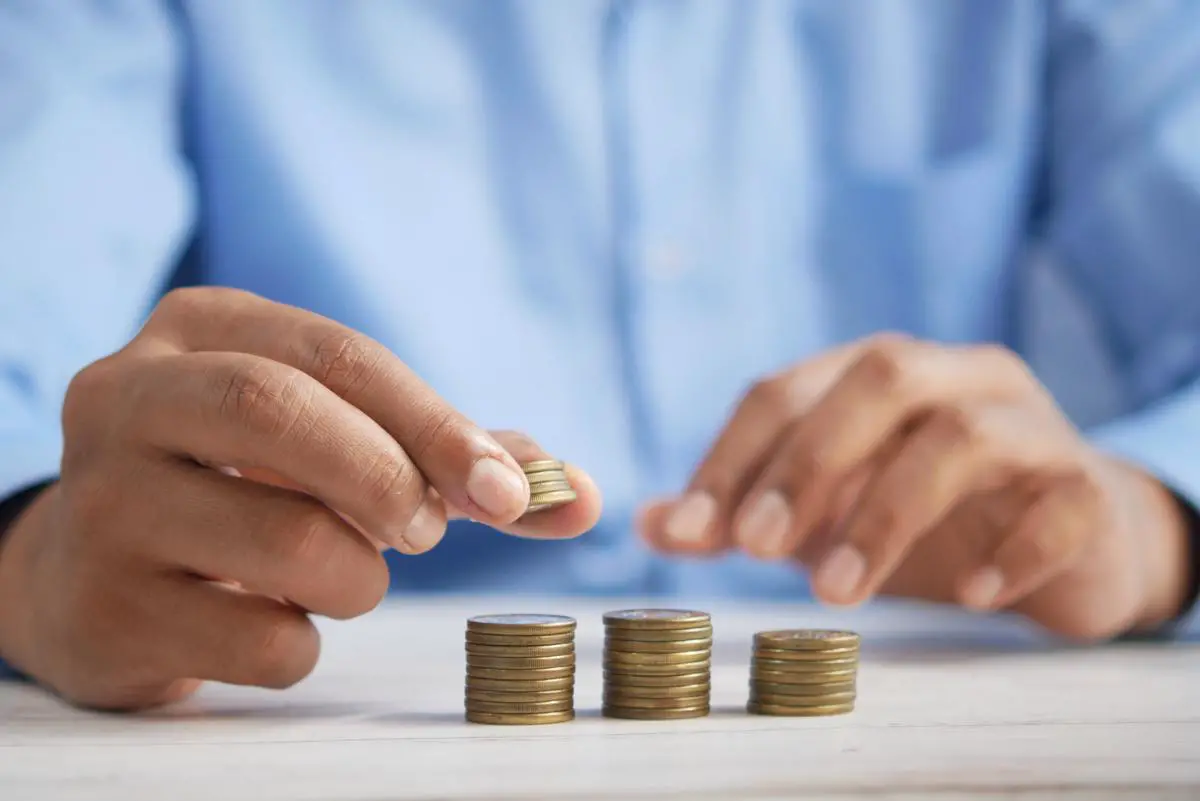 Image of a person managing coins, symbolizing strategies for minimizing expenses.